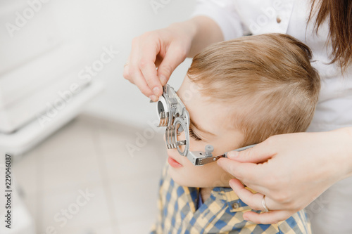 Pediatric Doctor ophthalmologist checks vision of child boy. Concept selection of glasses lenses.
