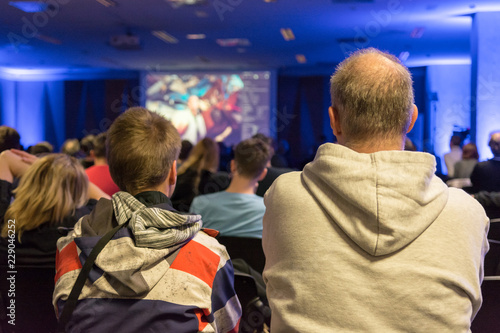 People listening to presentation at indoor conference.