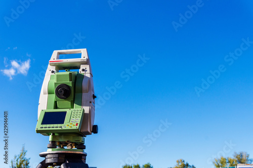 Surveyor equipment (theodolit or total positioning station) on the construction site of the motorway or road with blue sky in background