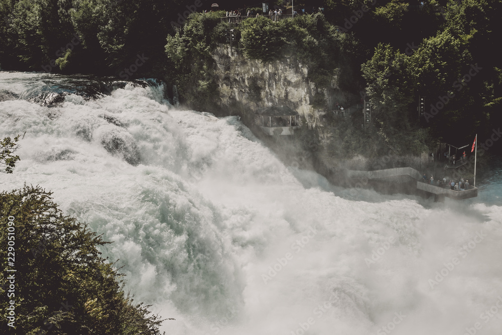 The Rhine Falls is the largest waterfall in Europe in Schaffhausen, Switzerland. Summer day with sun. View from rock