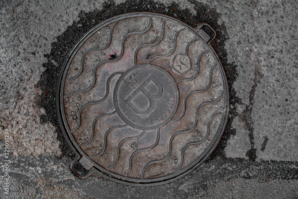 Manhole cover in the road of asphalt