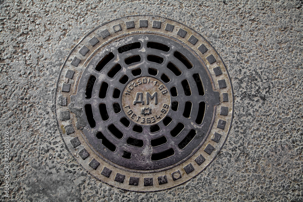 Manhole cover in the road of asphalt