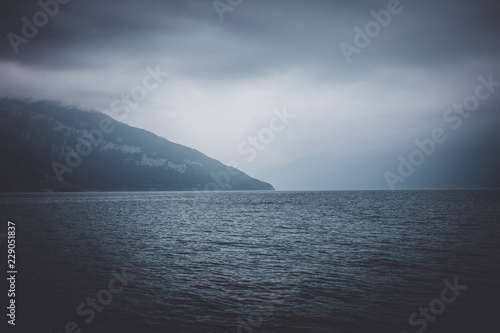 View on lake Thun and mountains from ship in city Spiez, Switzerland, Europe. Dramatic moody blue clouds scene