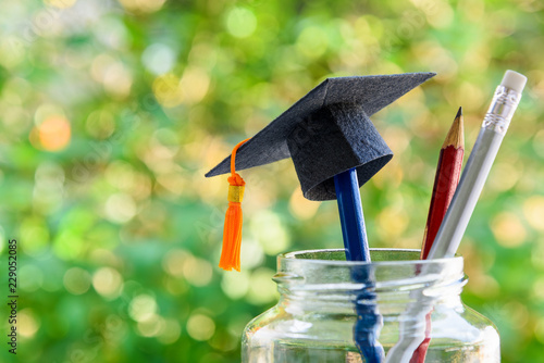 Back to school or graduate certificate program concept : Black graduation cap on a pencil in a bottle. Back to school is the period in which students prepares school supply for upcoming school year. photo