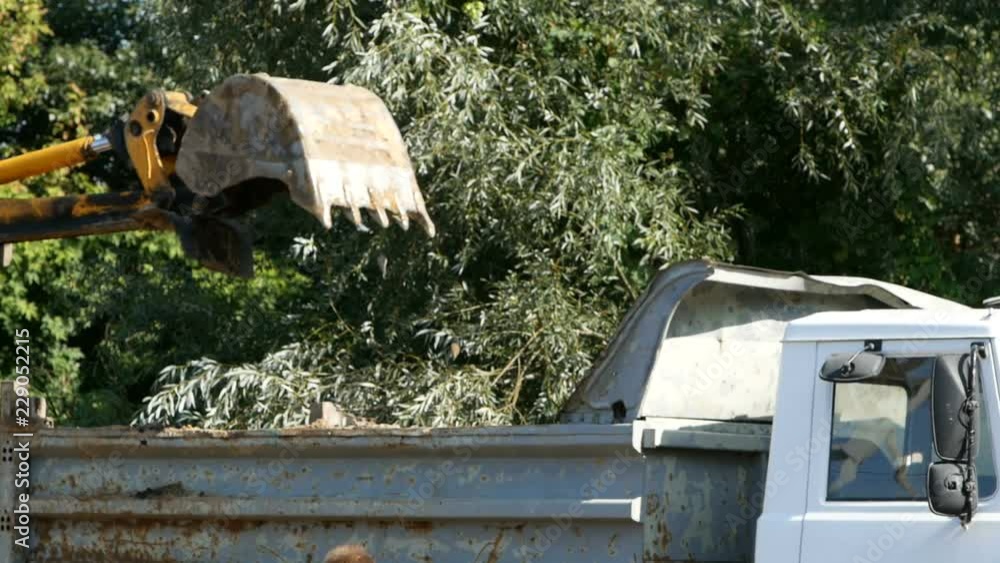 Excavator digs a pit. construction of an industrial building foundation. empty truck pulls up to an excavator and changes a full truck Excavator digs a pit. construction of an industrial building foundation. empty truck pulls up to an excavator and changes a full truck