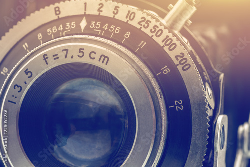 Close-up detailed photo of the optical lens of a nostalgic old retro 35mm negative film camera with f-stop and focal length number, retouched by removing out the dust and rust, vintage filter effect.