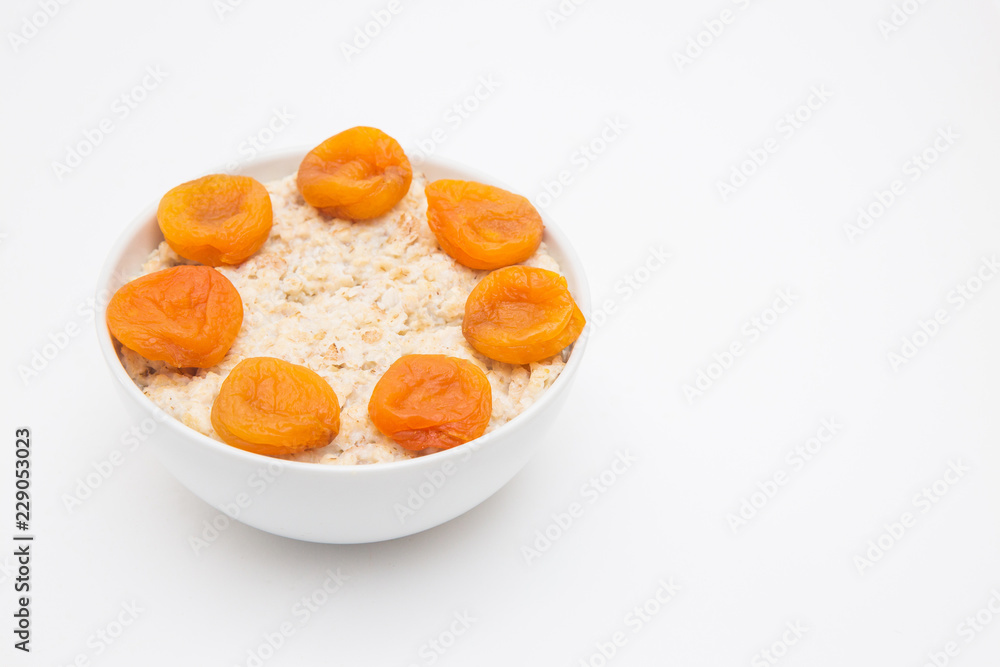 Oatmeal with dried apricots in white bowl on white bakcground. Isolated on white. Healthy food Oatmeal with dried apricots in white bowl on white bakcground. Isolated on white. Healthy food