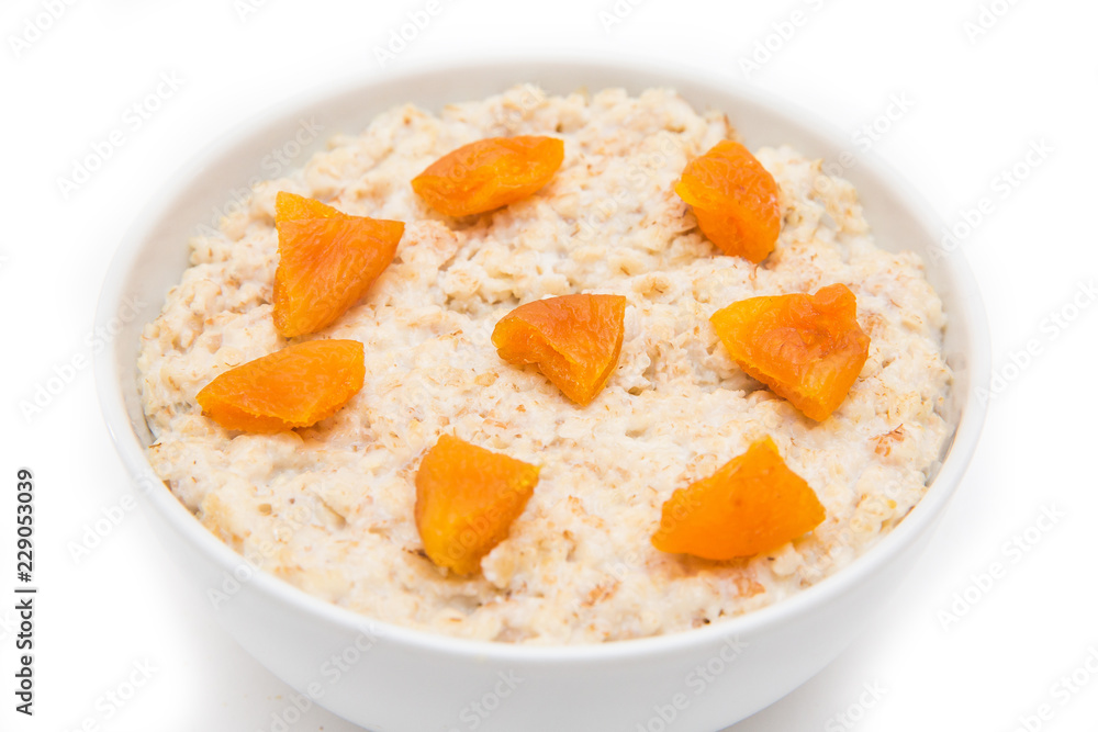 Oatmeal with dried apricots in white bowl on white bakcground. Isolated on white. Healthy food Oatmeal with dried apricots in white bowl on white bakcground. Isolated on white. Healthy food