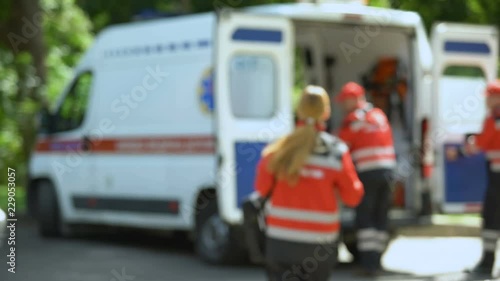 Paramedic looks at camera, getting into ambulance, patient's transportation