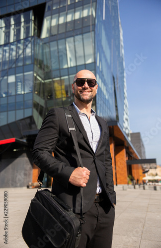 Handsome elegant businessman with sunglasses in front of office building