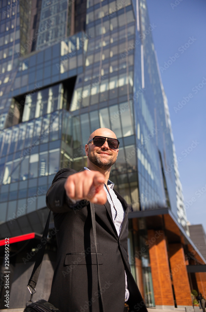 Handsome elegant businessman with sunglasses in front of office building