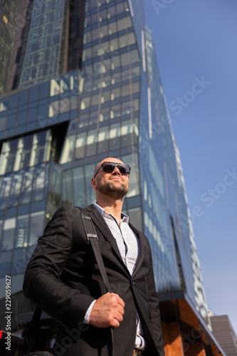 Handsome elegant businessman with sunglasses in front of office building
