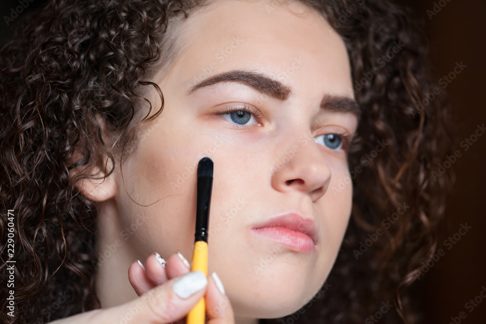 Closeup portrait of beautiful woman getting professional make-up with brush. Beauty and makeup concept Closeup portrait of beautiful woman getting professional make-up with brush. Beauty and makeup concept