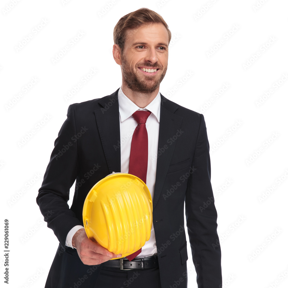 portrait of businessman holding helmet smiling and looking to side portrait of businessman holding helmet smiling and looking to side