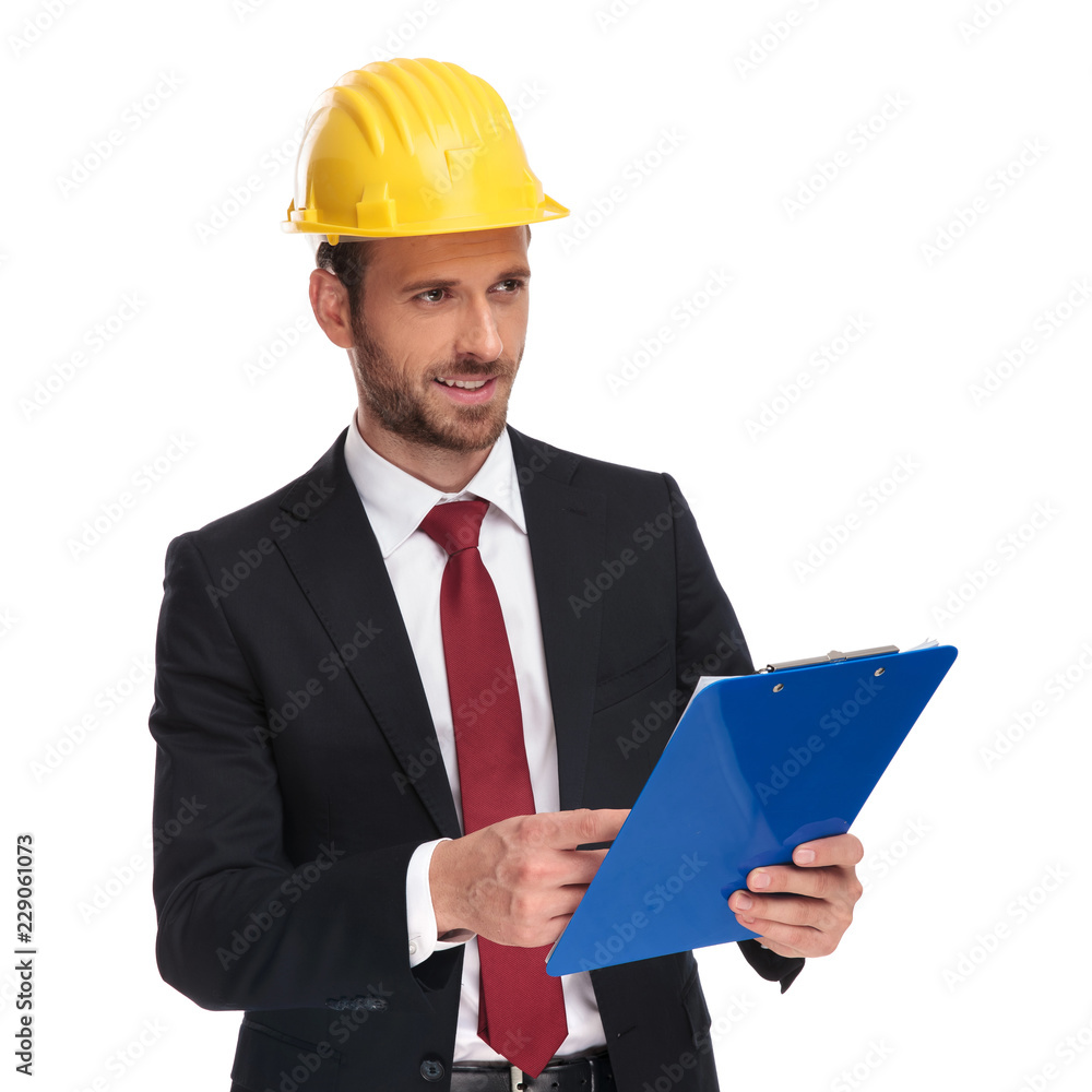 young engineer ceo holding blue clipboard looks to side young engineer ceo holding blue clipboard looks to side