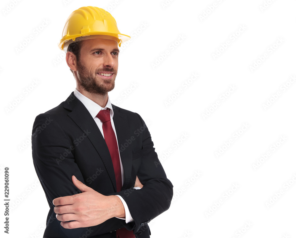 confident businessman wearing a yellow helmet looks up to side confident businessman wearing a yellow helmet looks up to side