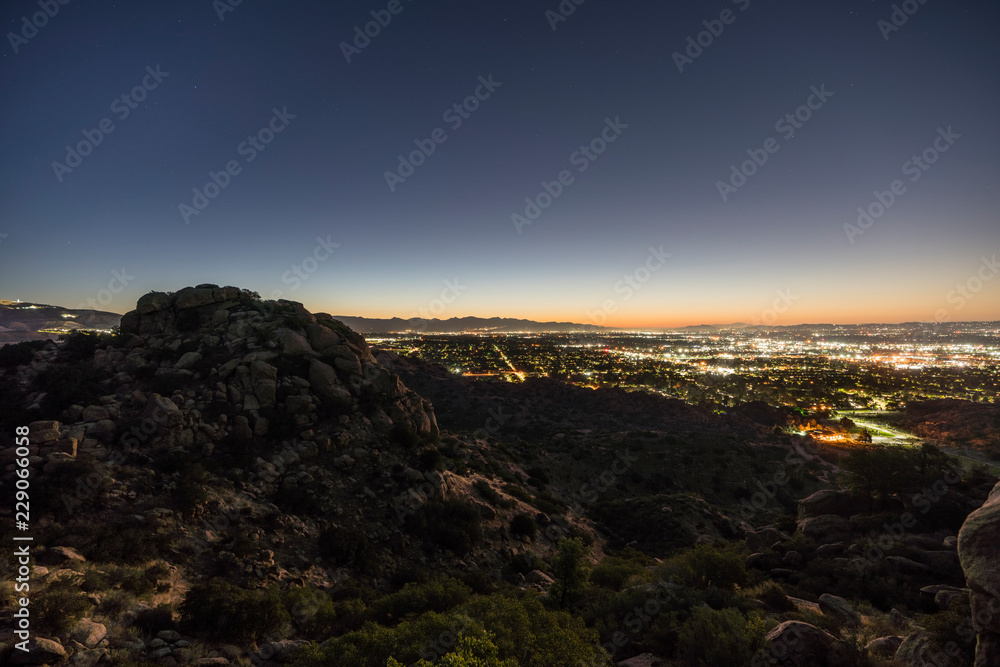 Los Angeles California predawn rocky hilltop view of the San Fernando Valley.  Burbank, North Hollywood, Griffith Park and the San Gabriel Mountains are in background.  
