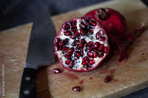 Juicy pomegranate on a cutting board on dark background photo