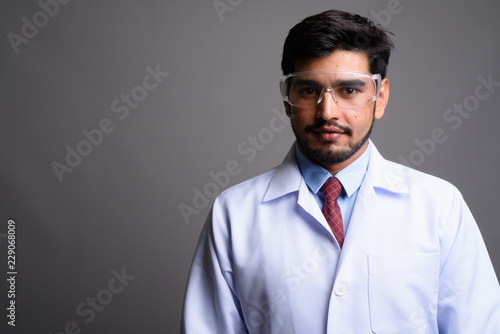 Young handsome bearded Persian man doctor wearing protective gla