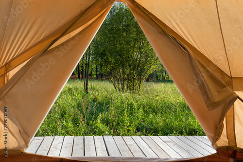 View from the canvas tent upon the green meadow photo