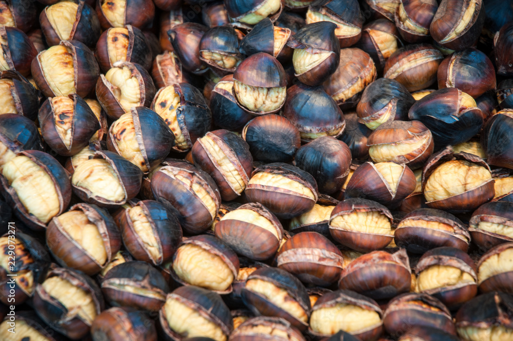 Roasted chestnuts in a frying pan by a street vendor . Roasted chestnuts in a frying pan by a street vendor .