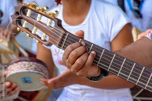 Detail of guitarist's hands and his acoustic guitar at an outdoor samba presentation photo