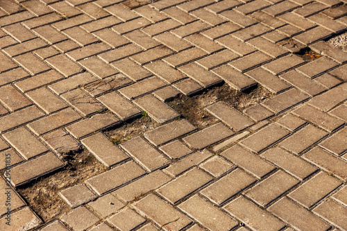 Damaged asphalt road with potholes, caused by freeze-thaw cycles in winter. Bad road. Broken pavements sidewalks on sidewalk. pavement with paving slabs with defects and cracks coming in perspective photo