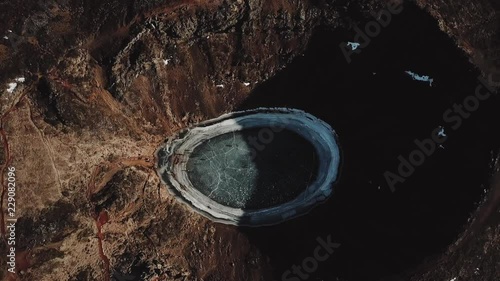 Aerial: Volcanic crater filed with frozen water. Kerid crater lake. Iceland