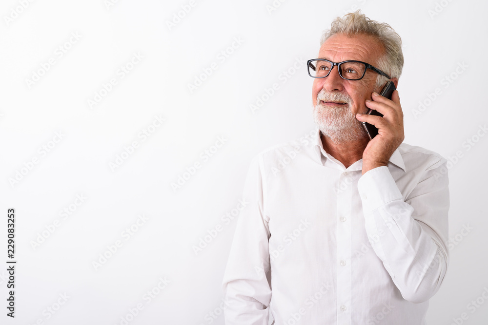 Studio shot of happy senior bearded man smiling and thinking whi Studio shot of happy senior bearded man smiling and thinking whi