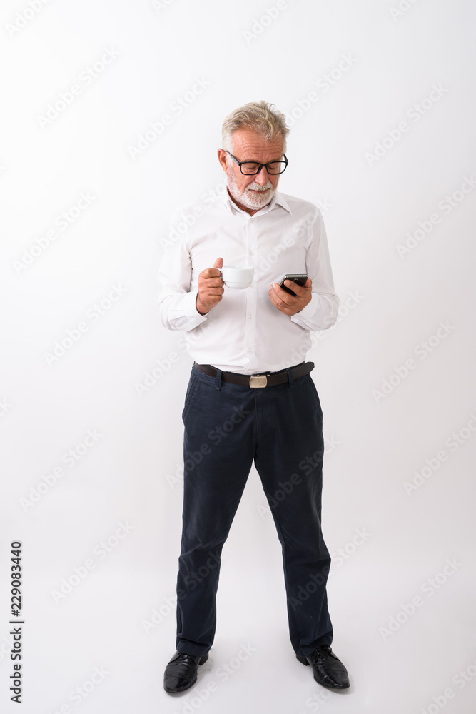 Full body shot of handsome senior bearded man standing while usi Full body shot of handsome senior bearded man standing while usi