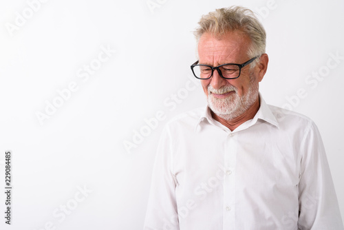 Studio shot of sad senior bearded man thinking while looking dow