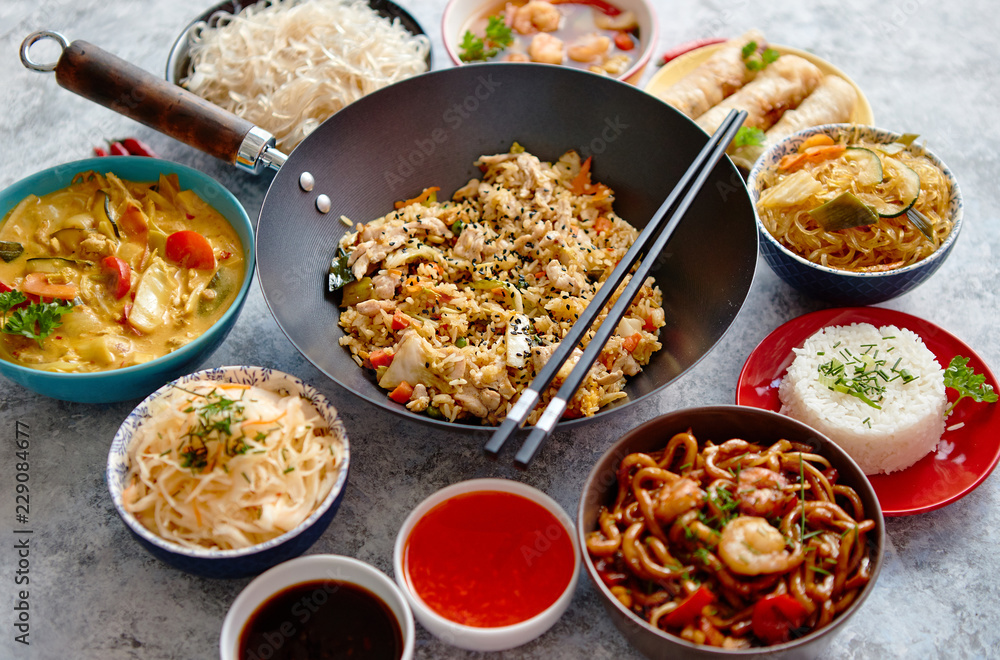 Chinese food set. Chinese noodles, fried rice with chicken, tom yum soup, spring rolls, deep fried fish and udon. Top view. Asian style food concept composition.
