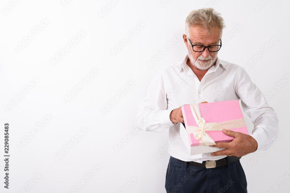 Studio shot of handsome senior bearded man opening gift box with Studio shot of handsome senior bearded man opening gift box with