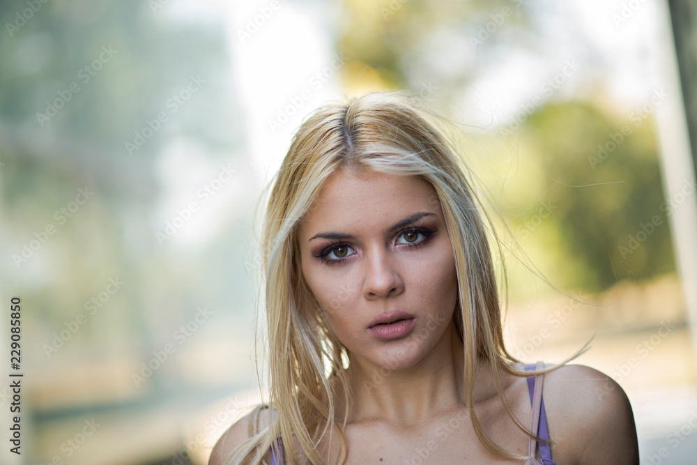 Photographing a girl during autumn near a high-tech glass building with a blurred background of the park