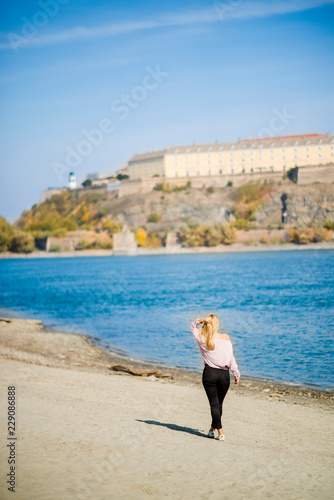 Photographing a girl during autumn on a beach near a river with a blurred background