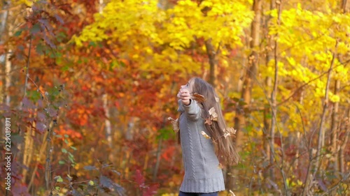 Happy girl playing and having fun in the autumn park, throws up leaves and laughs