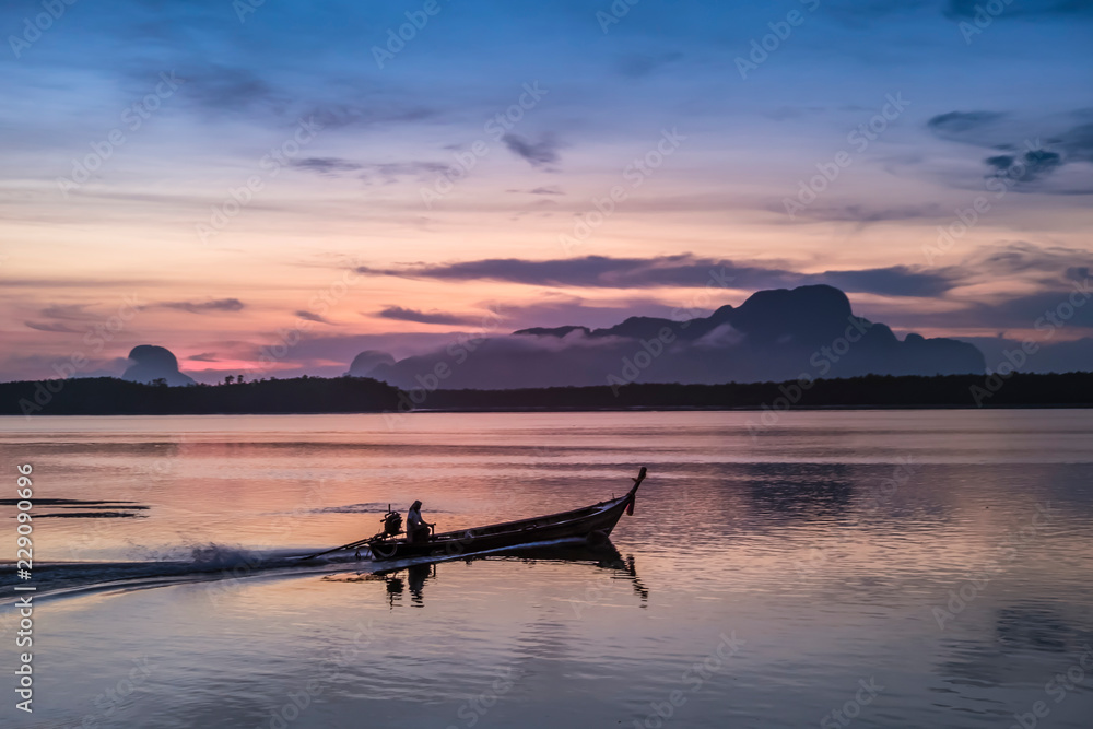 Silhouette of a fisherman on fishing Boat at Fisherman village on sunrise in Sam Chong-tai, Phang Nga, Thailand