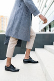 Close-up of unrecognizable African businessman in coat moving up stairs while going to work in office