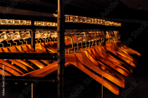Fototapeta Wooden hangers with numbers in dark cloakroom