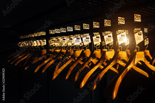Fotografie, Obraz Wooden hangers with numbers in dark cloakroom