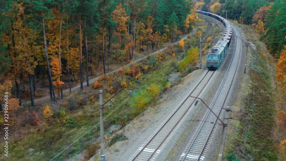 Aerial view of freight train carrying rubble rides through the autumn forest Aerial view of freight train carrying rubble rides through the autumn forest