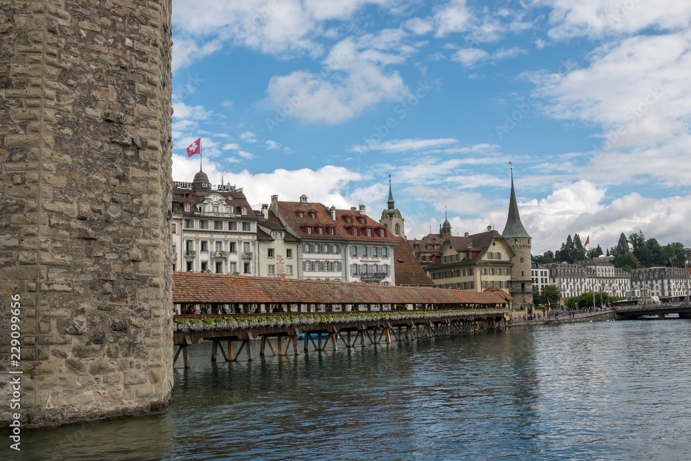 Lucerne, Switzerland - July 3, 2017: Panoramic view of city center of Lucerne with famous Chapel Bridge and river Reuss. Summer landscape, sunshine weather, dramatic sky and sunny day