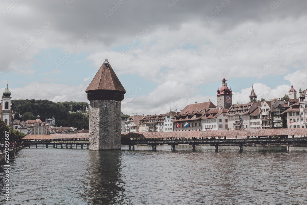 Lucerne, Switzerland - July 3, 2017: Panoramic view of city center of Lucerne with famous Chapel Bridge and river Reuss. Summer landscape, sunshine weather, dramatic sky and sunny day