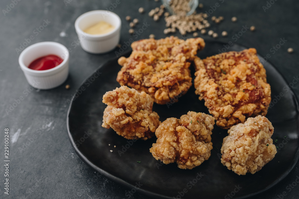 Chicken karaage japanese food in the black plate on grey concrete background with herb and flour Chicken karaage japanese food in the black plate on grey concrete background with herb and flour