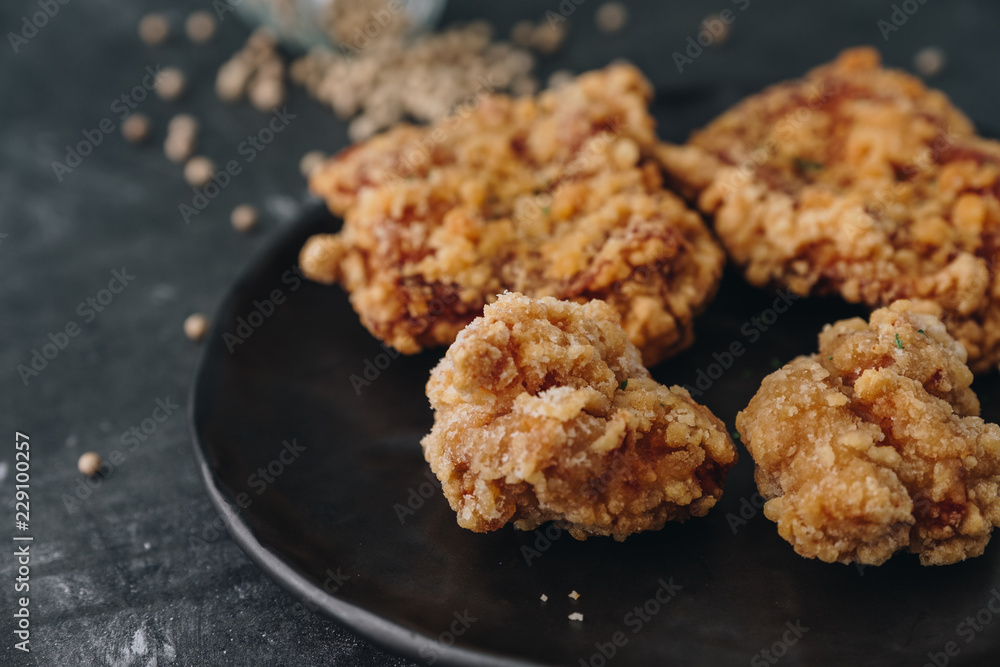 Chicken karaage japanese food in the black plate on grey concrete background with herb and flour Chicken karaage japanese food in the black plate on grey concrete background with herb and flour