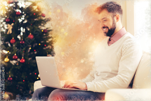 Work from home. Handsome bearded freelancer feeling extremely joyful and cheerful while working at home sitting near Christmas tree