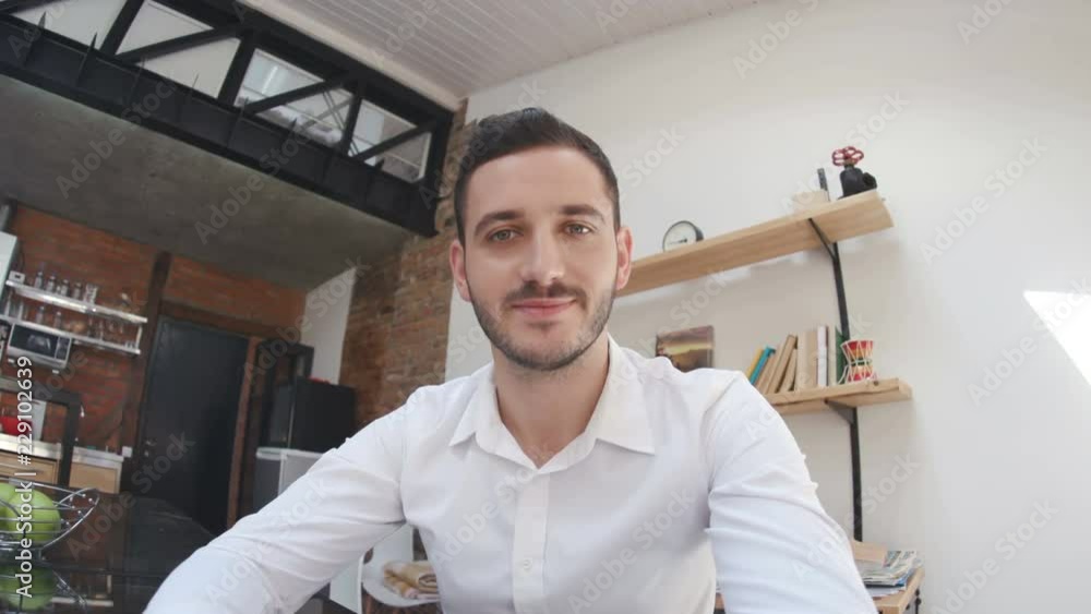 Gorgeous young man in white shirt looking directly into webcam,