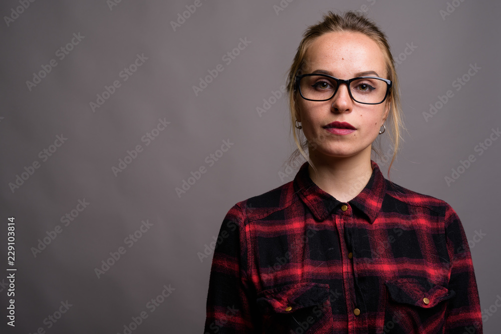 Obraz premium Young beautiful woman with blond hair wearing eyeglasses against