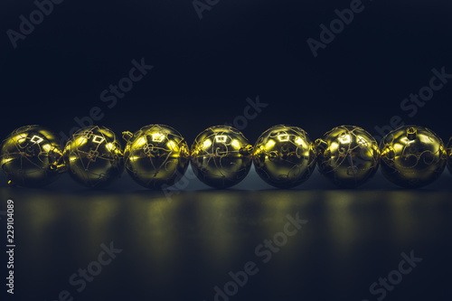 Golden Christmas balls on black background.