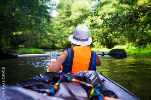 kayaking and canoeing. Young woman in boat with oars swims on wild river in jungl